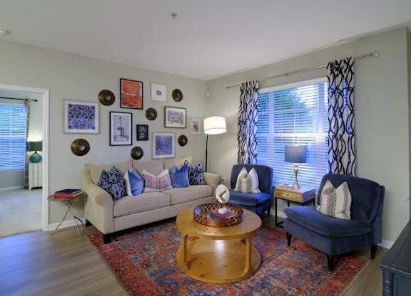 A living room with a couch, two chairs, a coffee table, and pictures on the wall.