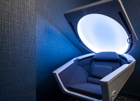 A futuristic chair with a glowing light on the back is placed in a room.