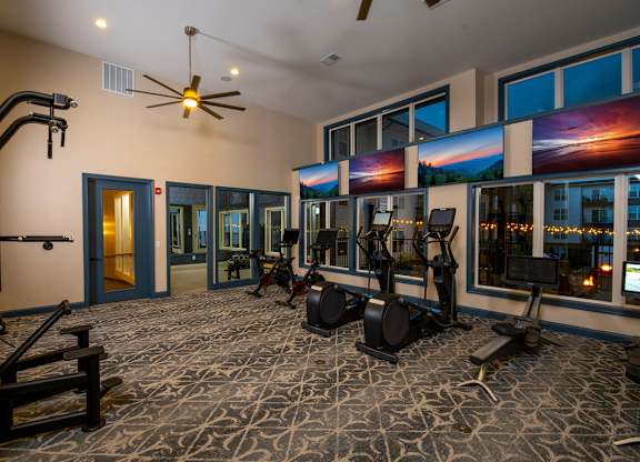 A gym with a variety of equipment including treadmills, weights, and a bench press.