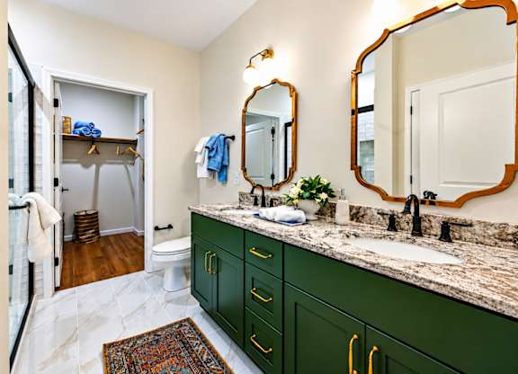 A bathroom with green cabinets and a marble counter.