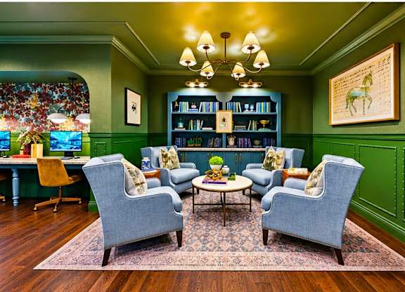 A living room with a green wall and a stained glass window.