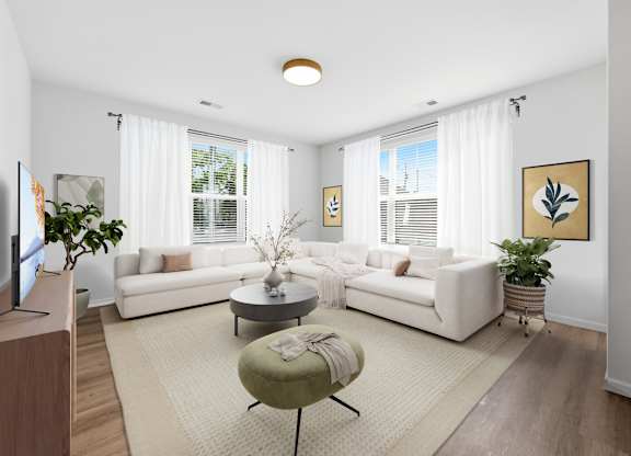 A living room with a white couch, a green ottoman, and a television on the left side.