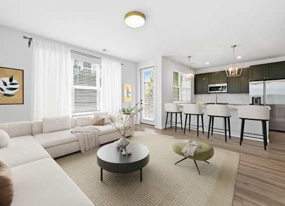 A modern living room with a white sofa, a coffee table, and a kitchen area in the background.