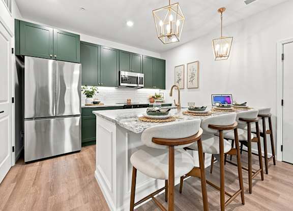 A kitchen with a white island and green cabinets.