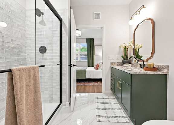 A bathroom with a green cabinet and a glass shower door.
