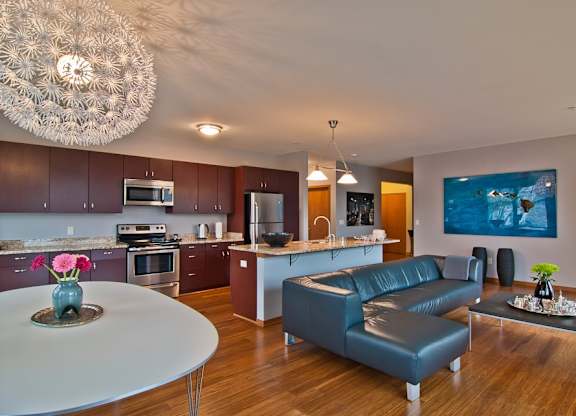 A modern kitchen with a blue sofa and a grey table at Cornerstone & Ravenna* Apartments, Wisconsin