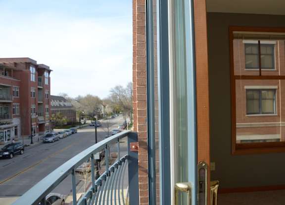A view of a street from a window with a balcony at Cornerstone & Ravenna* Apartments, Shorewood, WI