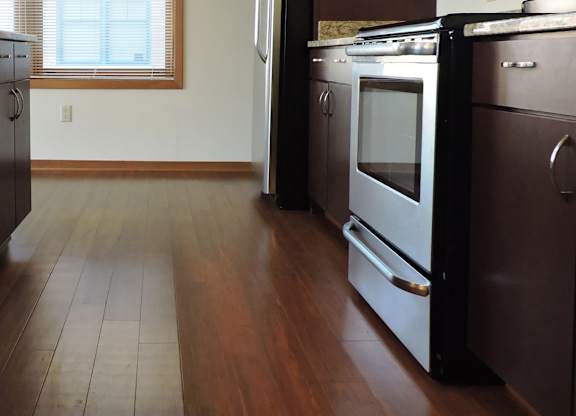 A kitchen with dark wood floors and stainless steel appliances at Cornerstone & Ravenna* Apartments, Shorewood