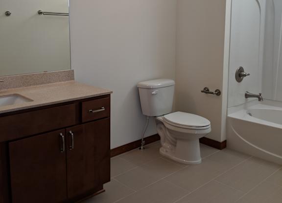 A white toilet sits in a bathroom next to a sink and a bathtub at Cornerstone & Ravenna* Apartments, Wisconsin, 53211