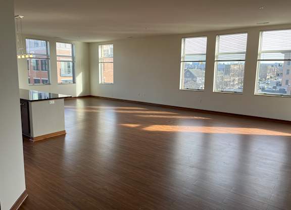 A large empty room with wooden floors and windows at Cornerstone & Ravenna* Apartments, Shorewood 53211