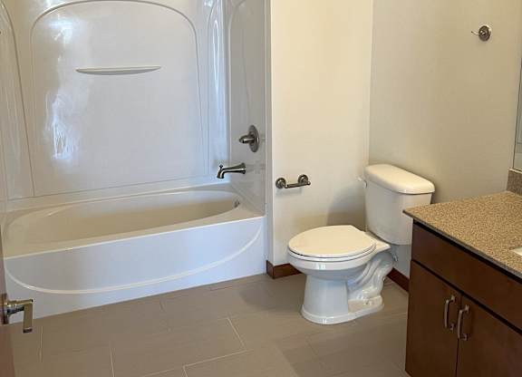 A white toilet sits next to a bathtub in a bathroom at Cornerstone & Ravenna* Apartments, Shorewood