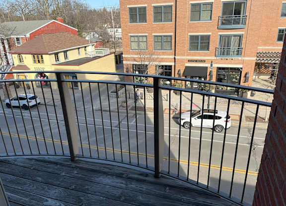 A view of a street from a balcony with cars parked on the side at Cornerstone & Ravenna* Apartments, Shorewood, Wisconsin