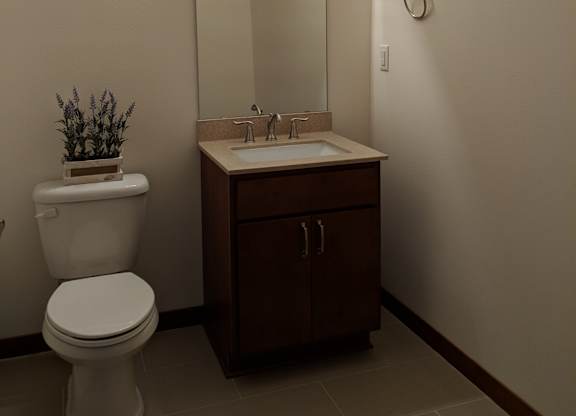 A white toilet sits next to a sink in a bathroom at Cornerstone & Ravenna* Apartments, Shorewood, WI
