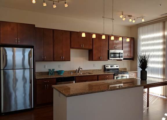 A kitchen with brown cabinets and a granite counter top at Cornerstone & Ravenna* Apartments, Wisconsin, 53211