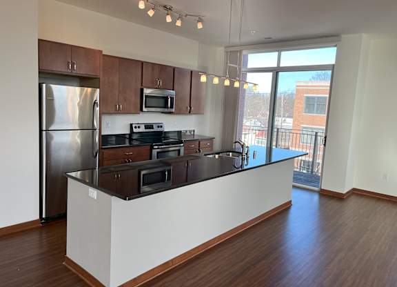 A kitchen with wooden cabinets and a stainless steel refrigerator at Cornerstone & Ravenna* Apartments, Shorewood, WI