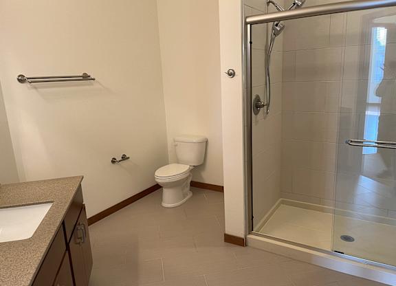 A white toilet in a bathroom with a walk-in shower at Cornerstone & Ravenna* Apartments, Shorewood, WI