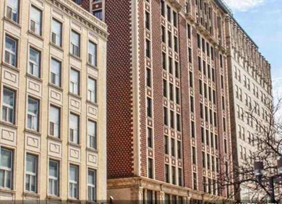 A tall building with a red brick facade stands between two shorter buildings.
