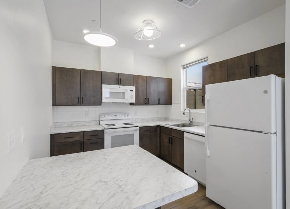 a kitchen with white marble counter tops and wooden cabinets and a refrigerator