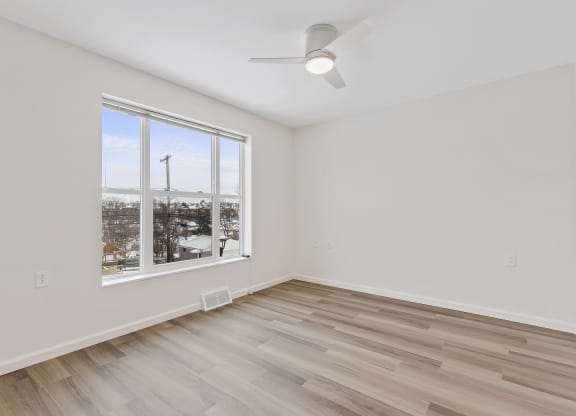 an empty living room with a large window and wooden floors