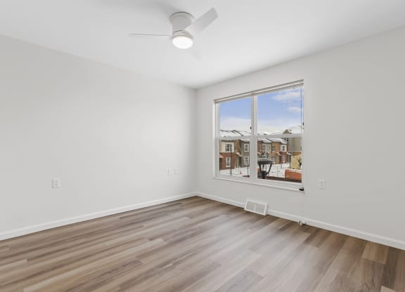 an empty living room with a large window and wooden floors