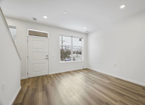 a living room with white walls and a window and a door