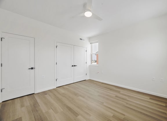 a living room with white walls and wooden floors and a window