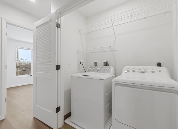 a white laundry room with two washes and a dryer