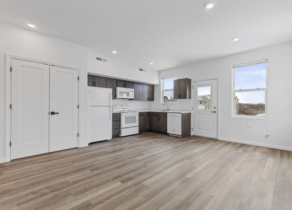 an open kitchen and living room with white walls and wooden floors