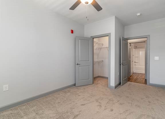 a bedroom with a ceiling fan and a closet with two doors at The Parker Myrtle Beach, Myrtle Beach