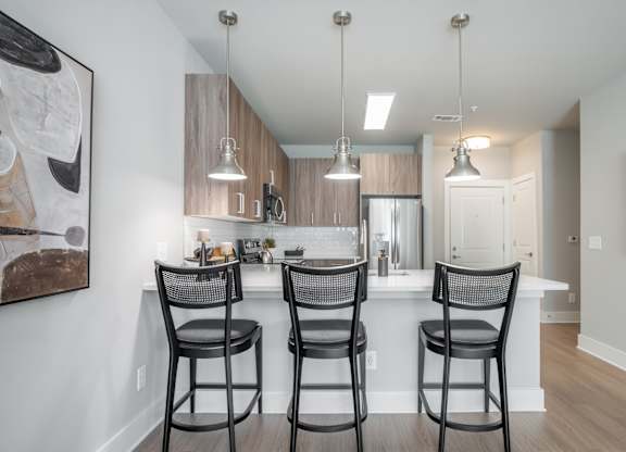A kitchen with a bar area and chairs.