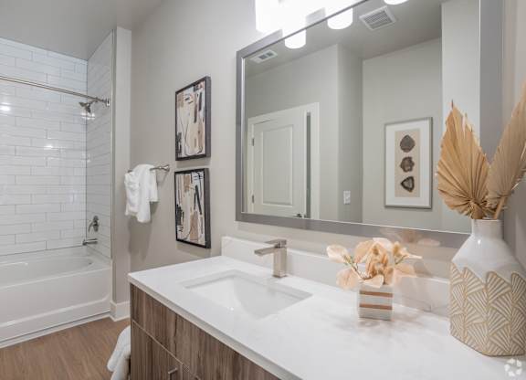 A white sink in a bathroom with a white tub and a mirror.