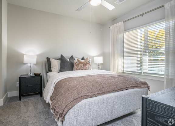 A bedroom with a bed, pillows, and a lamp.