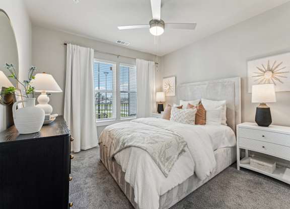 A bedroom with a large bed, a nightstand, and a ceiling fan at The Hendry Apartments, Fort Myers