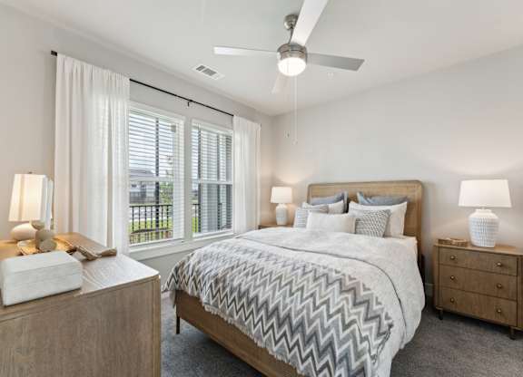 A bedroom with a large bed, a ceiling fan, and a window with blinds at The Hendry Apartments, Fort Myers, FL, 33905