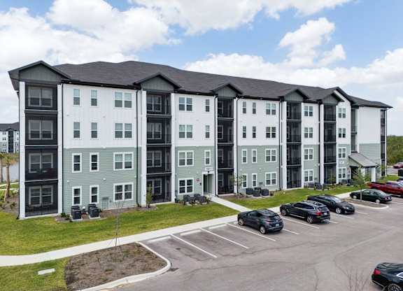 A large apartment complex with a parking lot in front at The Hendry Apartments, Fort Myers, FL