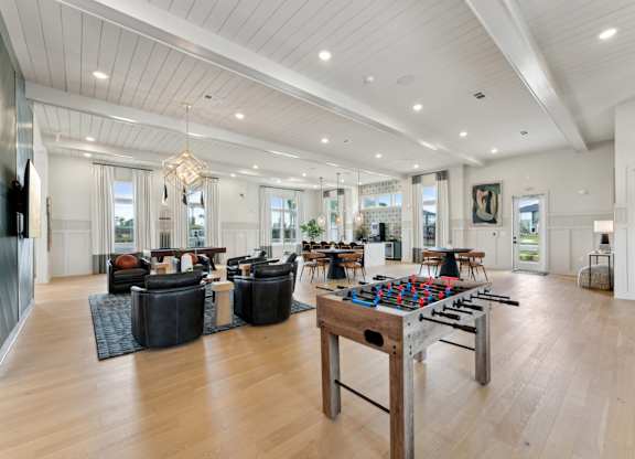 A spacious living room with a large wooden table and comfortable seating at The Hendry Apartments, Fort Myers