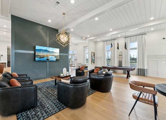 A living room with a large screen tv and a wooden floor at The Hendry Apartments, Fort Myers, Florida