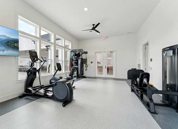 A spacious gym with a variety of equipment including treadmills, stationary bikes, and weight machines at The Hendry Apartments, Fort Myers, Florida