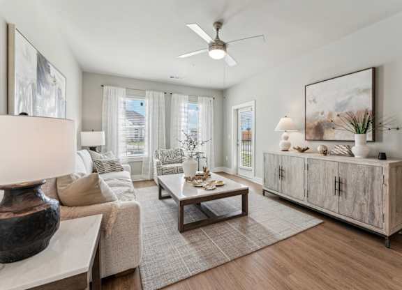 A living room with a couch, a coffee table, and a large painting on the wall at The Hendry Apartments, Fort Myers, 33905