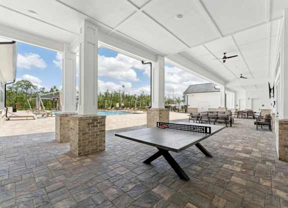 A patio with a table and chairs is covered by a white roof at The Hendry Apartments, Fort Myers, FL