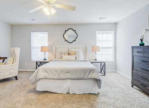 A bedroom with a large bed, a chair, and a ceiling fan.