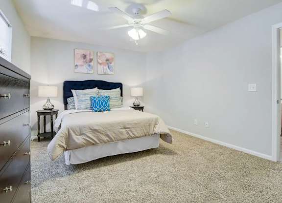 A bedroom with a bed, nightstand, and a ceiling fan.