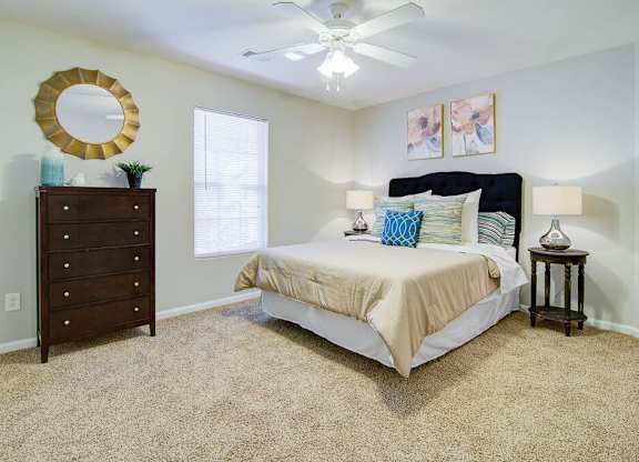A bedroom with a bed, dresser, and a ceiling fan.