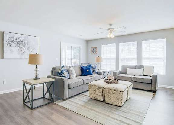A living room with a grey couch, a white coffee table, and a large painting on the wall.