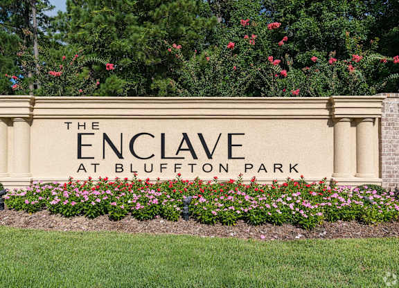 A sign that says "The Enclave at Bluffton Park" is surrounded by flowers.