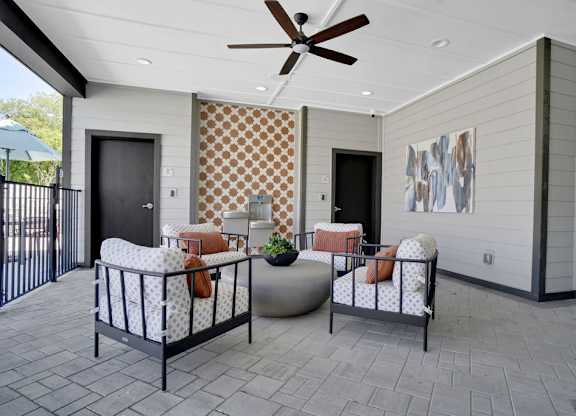 A patio with a black metal fence and a ceiling fan.