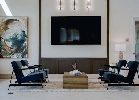 A living room with a large painting on the wall and a TV mounted above a coffee table.