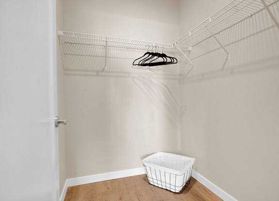 A white closet with a basket on the floor.