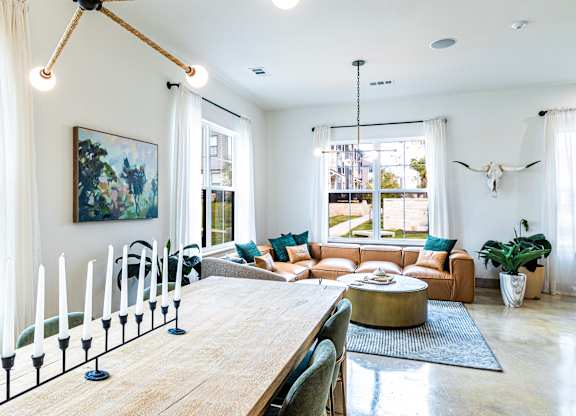 Living room and dining room with a wooden table and a large window at The Parker Austin, Pflugerville, TX