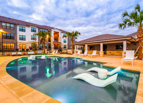 Swimming pool with chairs and a building in the background at The Parker Austin, Pflugerville, 78660